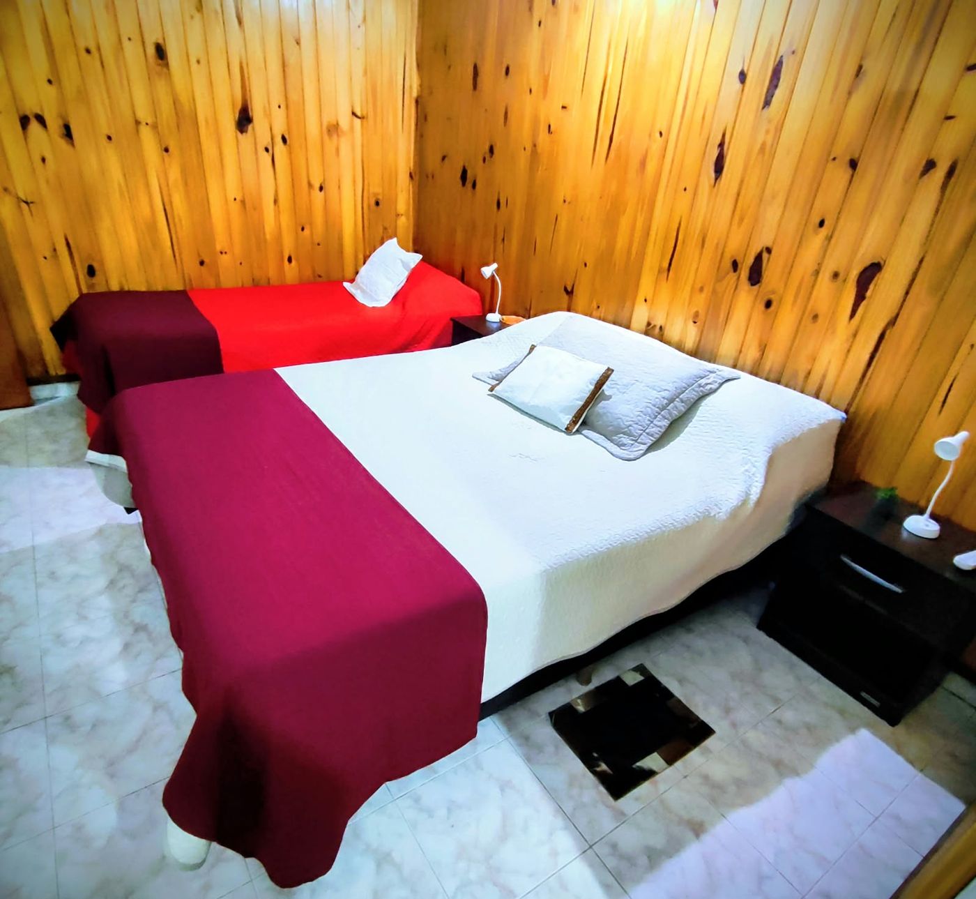 Habitación con paredes de madera y camas tendidas